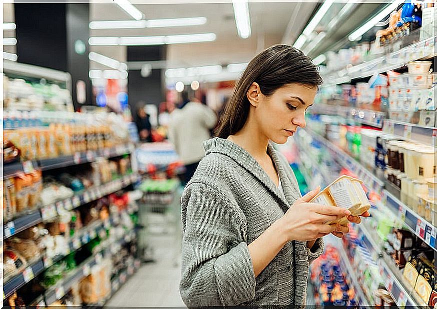 Woman with yogurt in supermarket checking food safety