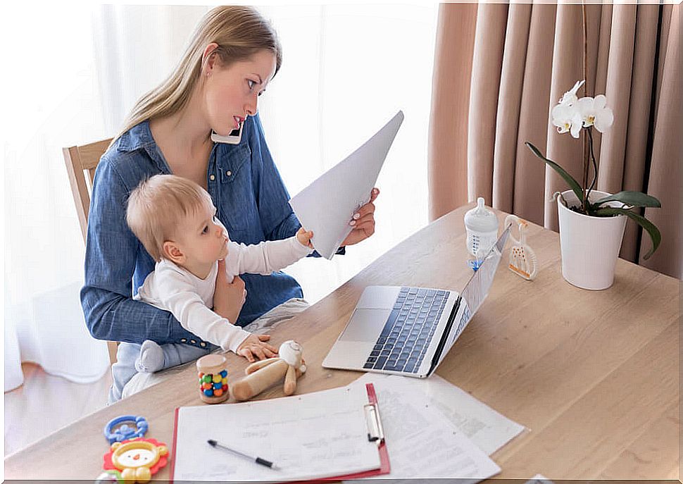 Woman in front of the computer working with her little one in her arms