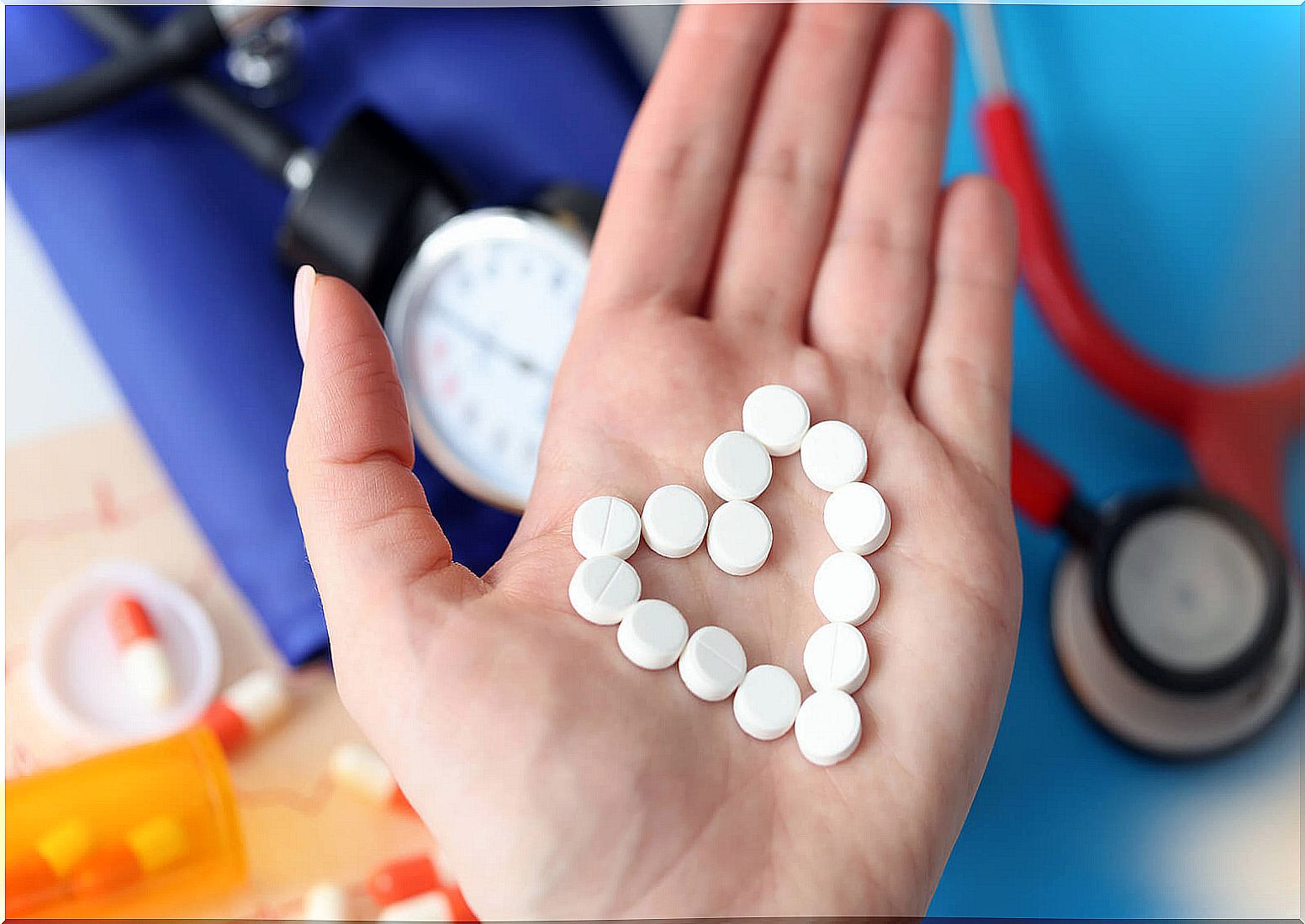 Woman holding several pills making a heart shape.